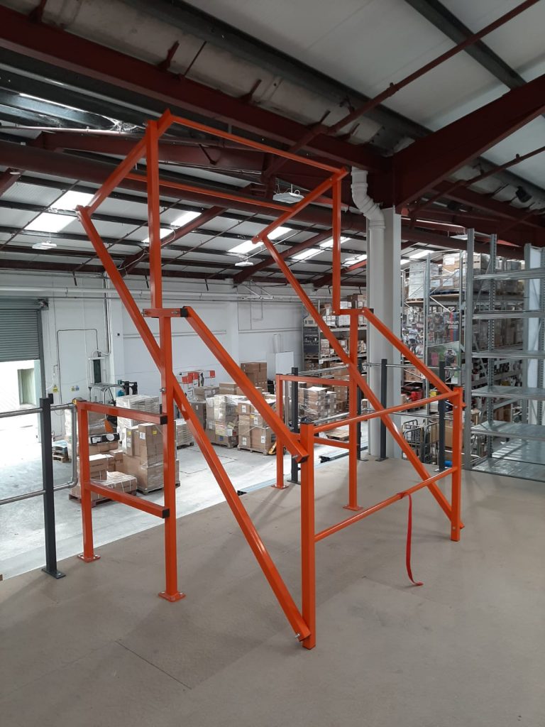 Orange epoxy powder coated high pallet gate installed on a mezzanine, complete with handrails.